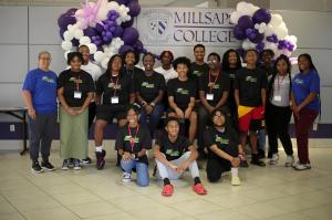 A group of C.O.O.L. high schoolers are pictured with their SR1 Summer Camp t-shirts on in front of a Millsaps banner with white and purple balloons.