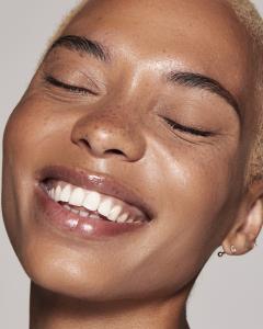 A young woman laughs, in this cosmetics product campaign
