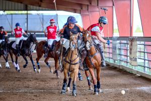 Two arena polo players on horses make a defensive manuever