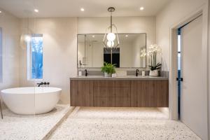 Wendy Glaister Interiors created an modern masterpiece, by creating calming colors, and wood textured cabinets and statement lighting alongside a wet room with soaking tub.