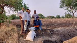 Image shows staff from Aumsat Technologies in a field using satellite technology to identify water sources.