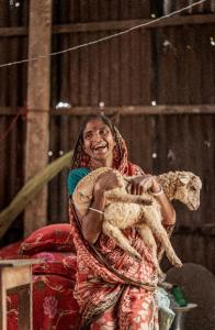 Image shows a young woman in Bangladesh holding a goat