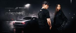 Two models wearing the Dodge Demon 170 by VENUM collection stand by a Dodge Challenger SRT Demon 170 car with a dark smoky background, lit only by a single lamp.