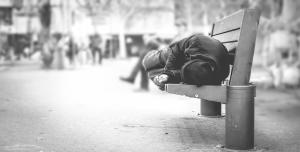 A homeless man sleeping on a bench. Eradicate Homelessness with Citygate