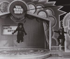 Drag queen Tootie Finnell takes a flying leap while singing Aretha Franklin's "Respect" as host Chuck Barris jumps along with her. In the '70s, openly gay & transgender contestants were showcased on "The Gong Show"