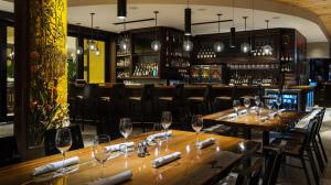Upscale restaurant bar with elegant wood accents, pendant lights, and set tables ready for guests.