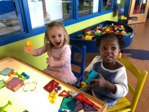 two young girl playing at light table with shapes