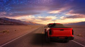 Red Chevy Colorado driving in the desert with an expanded Sawtooth Tonneau