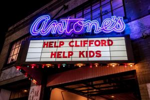 Neon marquee sign with Antone’s logo in blue announcing in red letters “Help Clifford Help Kids” at night