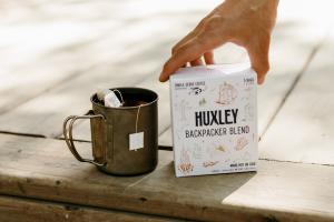 Huxley Backpacker Blend single-serve coffee brew bag in metal camping mug for easy outdoor use.