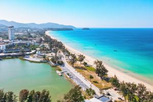 A panoramic view of the pristine sandy shores and azure waters of Karon Beach, renowned for its beauty and serenity, perfect for sun-seekers and water enthusiasts in Thailand's stunning Phuket region.