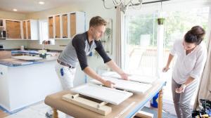 two homeowners painting their own kitchen cabinets