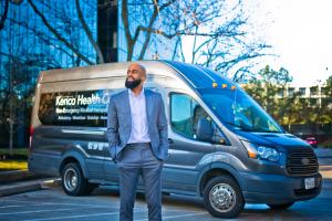Mike Morris, CEO of Kerico N.E.M.T. services looks off into the distance with his company's transport vehicle behind him.
