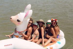 5 women sit together on a small inflatable llama raft while on a bachelorette part river rafting trip