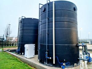 Two bulk storage tanks designed for pH balance at the Ogden Water Ltd facility. Shown at an angle outside on a gray cloudy day in a way that highlights the blue tubes coming out of the tanks.