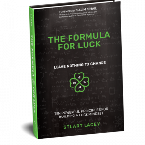 A graphic image of a book cover titled 'The Formula for Luck' by Stuart Lacey. The cover features a blackboard with mathematical and scientific formulas in white chalk, along with the phrase 'Leave Nothing to Chance' and a four-leaf clover symbol with a p