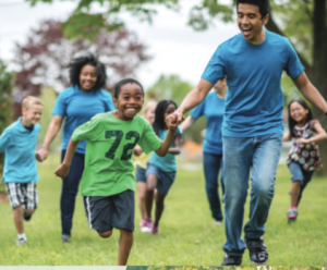 Camp counselor leading children in field games