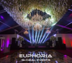 Here is the image depicting a luxurious wedding scene set in Marbella, complete with an optical dance floor, elegant chandeliers, and hanging wisteria flowers. The atmosphere created is one of sophistication and romance, highlighted by the vibrant and déc
