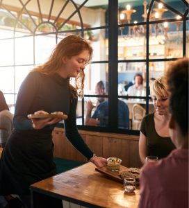 This is an image of the inside of a restaurant with a waitress serving patrons.