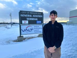 a student standing in front of a sign for VALT Enterprizes