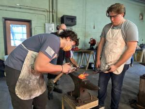 students hammering iron during the MSSM J-Term blacksmithing class