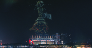 A FIFA Cup made of drones is above the night city