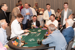 Group of men sitting around a poker table smiling.