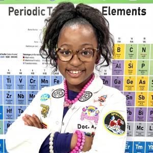 Ava N. Simmons standing in front of the Periodic Table of Elements in her STEM Mobile Lab