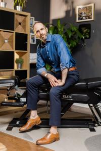 Dr. Joshua Gelber sitting on a chiropractic table at Annex Family Chiropractic