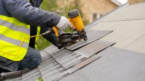 Photo of a roofer shingling a roof with a shingle gun