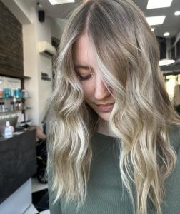 Stylist showing clients hair, which is a lived-in blonde balayage