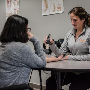 physical therapist performing laser therapy on patient