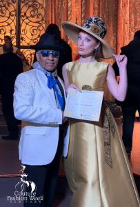 Designer Andres Aquino with a fashion model from his "Magical Muse" fashion show in New York City with a XIA coin certificate.