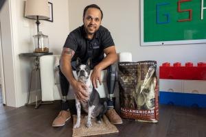 Jose Armenta U.S. Marine Corps Cpl. (Ret.) and his dog Oreo, pictured with their first complimentary bag of All-American food from Old Guard Pet Company in their specially adapted smart-technology home provided mortgage-free from the Gary Sinise Foundation.