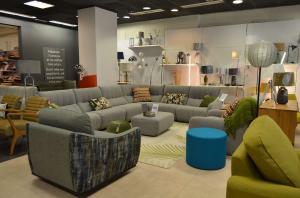 Photo showing large designer corner sofa, armchair and lighting display in furniture showroom