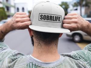 A man with backwards SOBRLIFE hat shows off his sober clothing in style