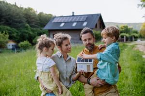 Happy family in front of their house with a solar panels on the roof.