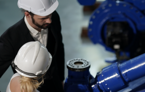 A man and a woman in hard hats next to industrial machinery.