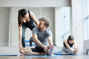 Female instructor helping a man stretch