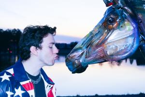 Opera  star turned metal-punk singer-songwriter Beaubie standing in front of a life size horse sculpture make of scrap metal located next to the lake in Fayetteville's Town at Trilith.