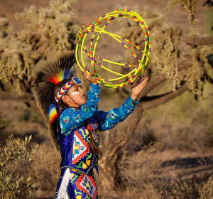 A Native American boy poses mid hoop dance while dancing in the desert