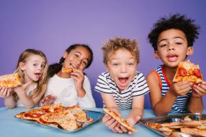 4 adorable kids happily eating pizza off of reusable, toxin-free stainless steel lunch trays.