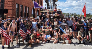 Participants of the Silkies Ruck March, wearing military silkies and carrying backpacks, gather for a group photo, showcasing their commitment to support veterans and first responders.