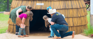 A family of four looking inside a big nipa hut.