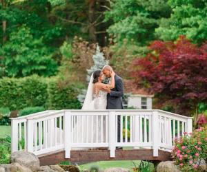 Couple on bridge over pond at Miraval Gardens by Wedgewood Weddings in East Bridgewater, MA