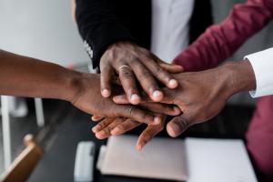 Black people stacking their hands in the center of the photo