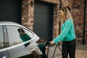 Woman charging electric vehicle with zappi home charger