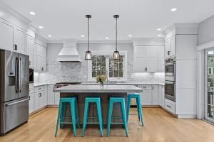 White kitchen cabinets, shaker style, with stainless steel appliances and an in the cabinet coffee maker.