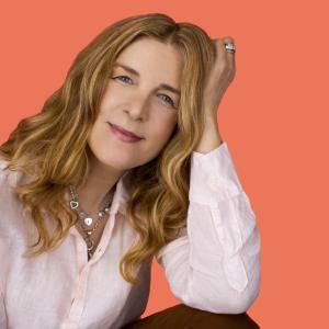 Image of vocalist and composer Jacqui Naylor by photographer Thomas Heinser for the artist's 2024 album Treasures of the Heart. Jacqui Naylor smiling, wearing soft pink linen shirt, orange background.