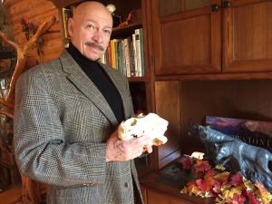 Dr. Charles Preston in a library holding an animal skull